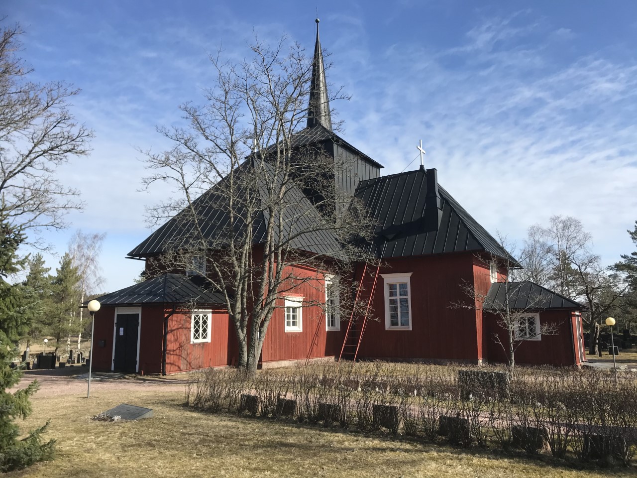 Yleisöopastus Hiittisten kirkossa Hitis röda träkyrka bland björklöv på hösten.