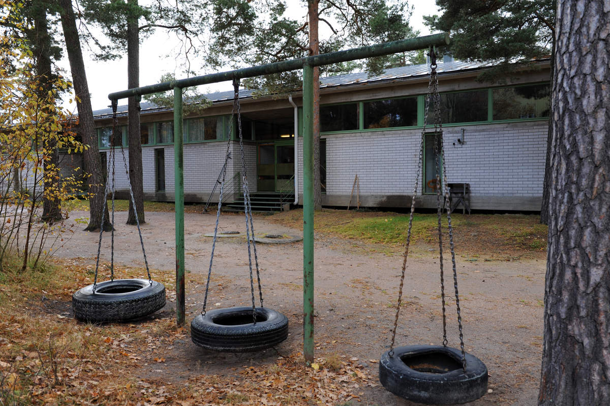 Taalintehtaan Kerhotalo on matala tiilirakennus. Etualalla kuvassa on kolme rengasta tehty vanhoista autonrenkaista. 